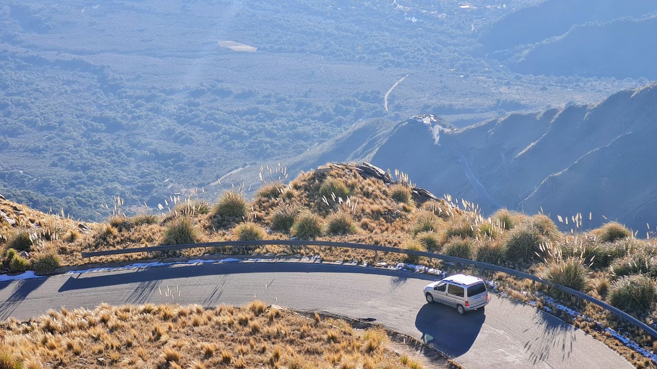 Ruta de montaña en Merlo, San Luis, con una combi blanca recorriendo el camino entre pastizales dorados